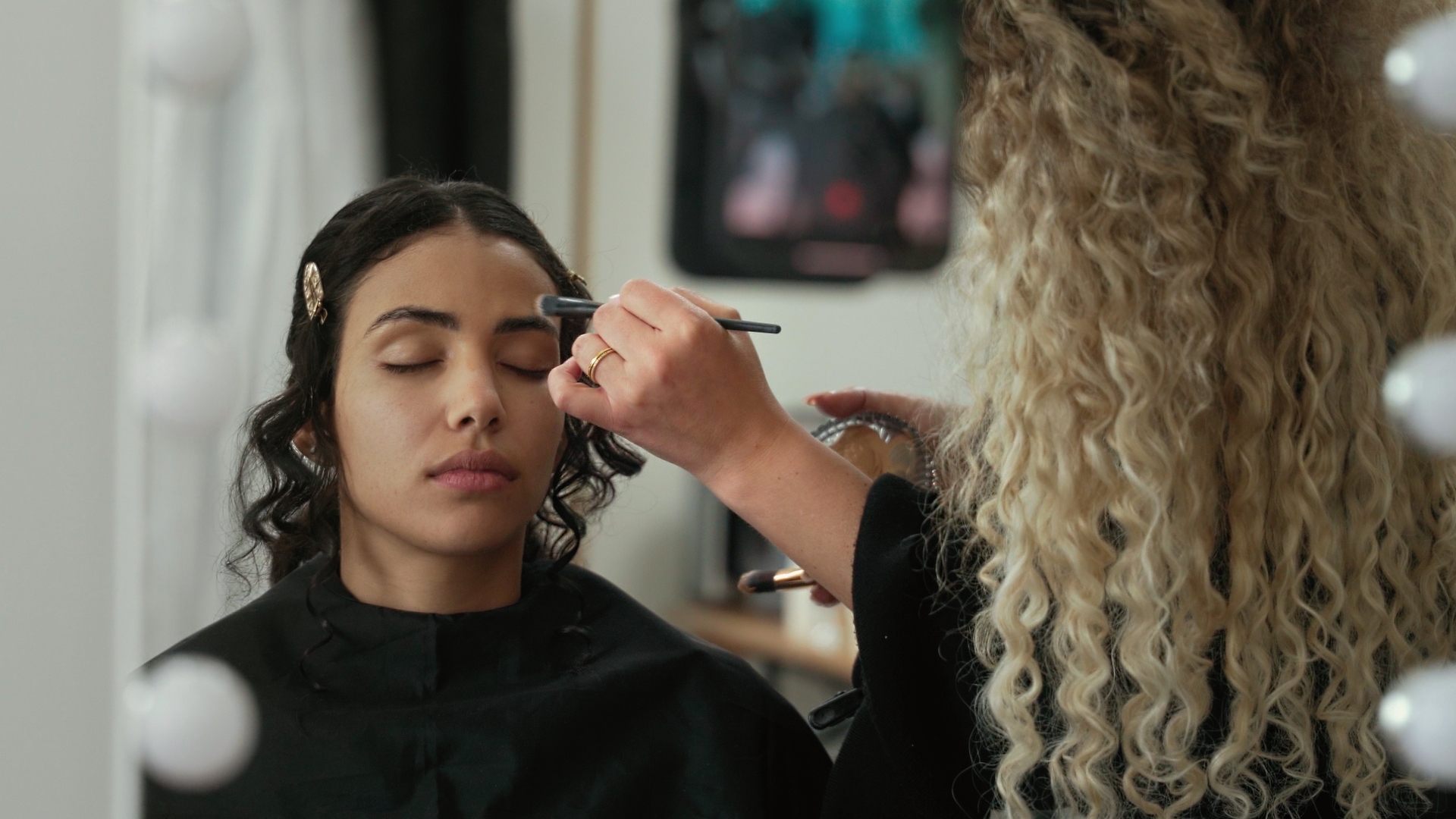 Junge Braut wird beim Getting Ready von einer Make-up Artistin geschminkt.