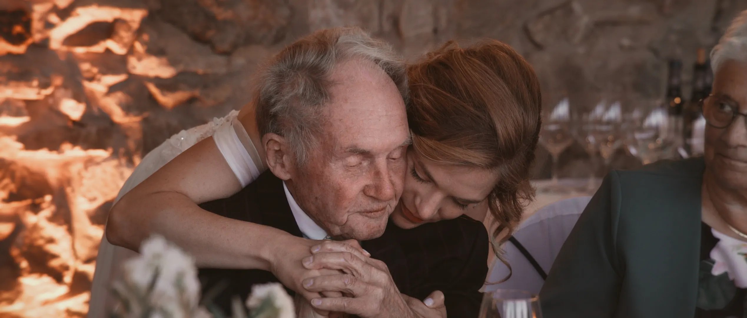 Innige Umarmung zwischen einer Braut und ihrem Großvater bei der Hochzeitsfeier.