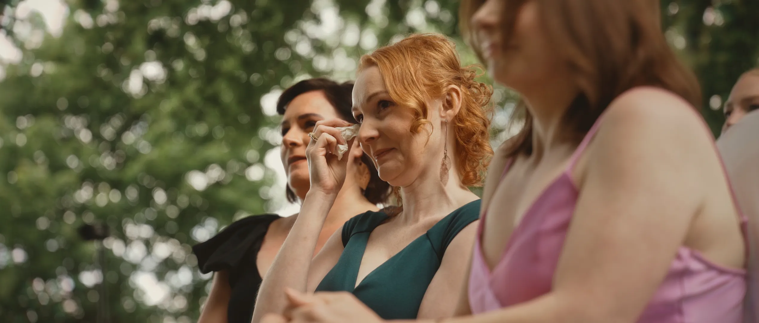 Drei junge Frauen sitzen mit Tränen in den Augen als Gäste in einer freien Trauung.